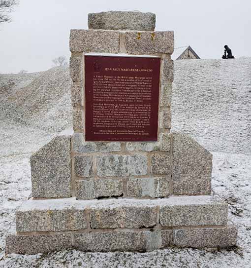 Monument en pierre enneigé avec une plaque marron.