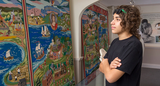  A young visitor examines the Fort Anne Heritage Tapestry hanging on the wall.