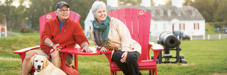 Un couple est assis sur les chaises rouges en profitant de la vue du lieu historique national du Fort-Anne.