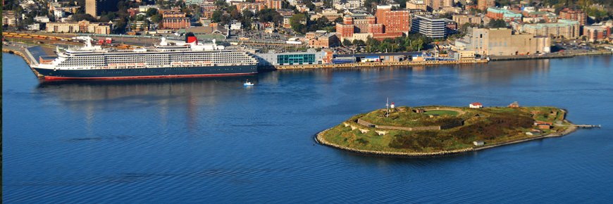 An aerial view of Georges Island, Halifax, and a large cruise ship in Halifax Harbour. The cruise ship appears to be larger than the Island. 