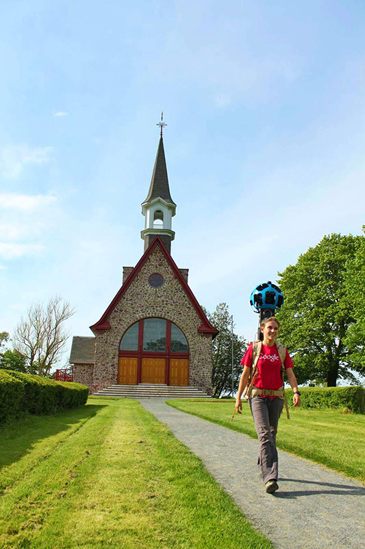 Une employée de Google marche devant l'église avec une caméra spécialisée attachée à son dos.