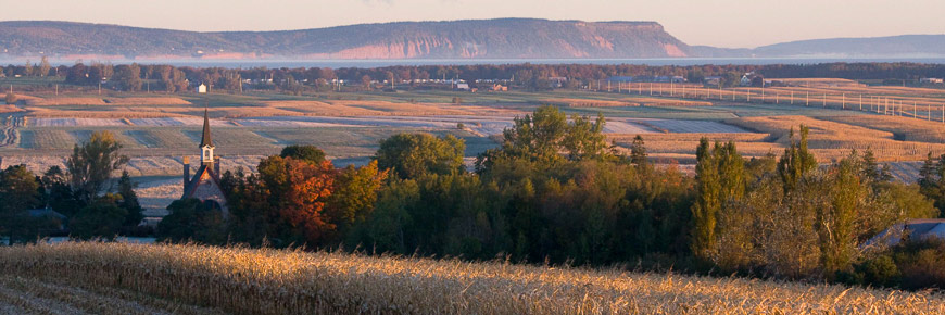 The landscape of Grand-Pré with the church and Blomidon Cape in the background