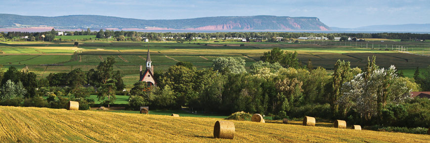 The landscape of Grand-Pré with the church and Blomidon Cape in the background