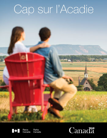 A couple sitting on red chairs looking at the landscape of Grand-Pré