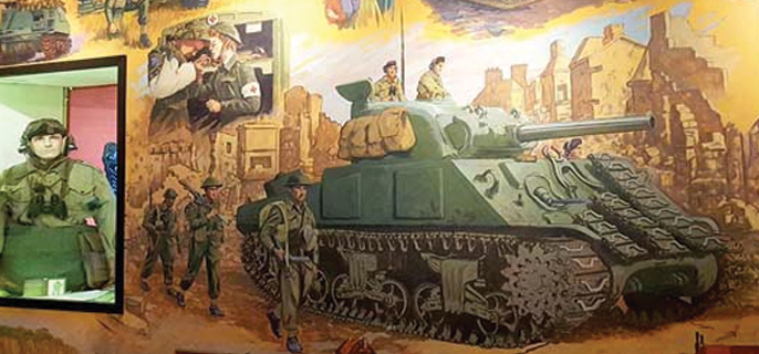An exhibit is shown with a portion of a mural featuring a scene from the Second World War and a display containing a mannequin in a soldier’s uniform.