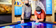Visitors lean over to interact with a digital exhibit.