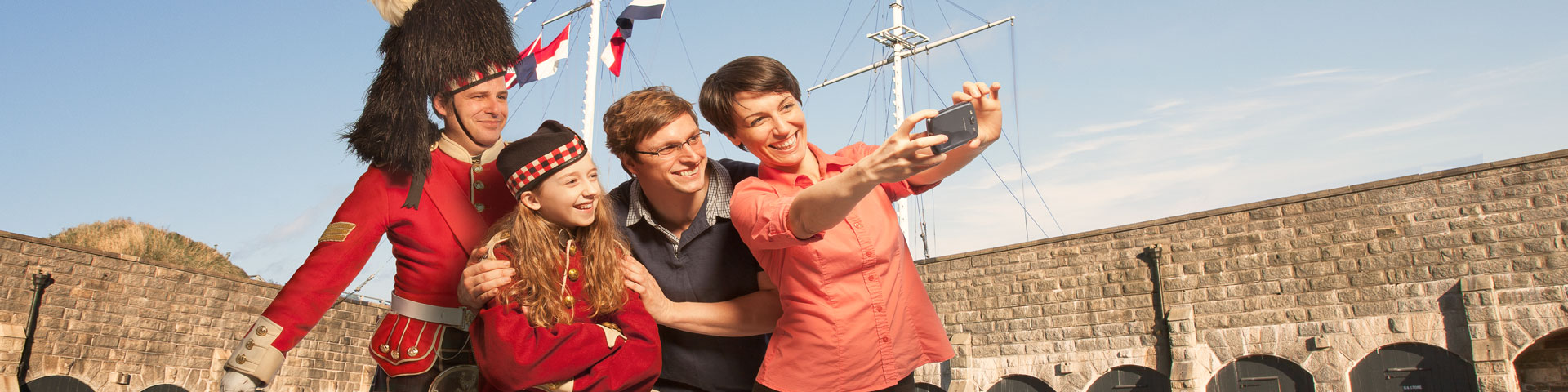 A Highlander poses with a family for a selfie. 