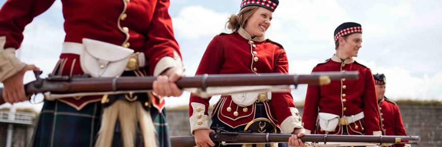 Smiling teens dressed in 78th Highlander uniforms holding riffles