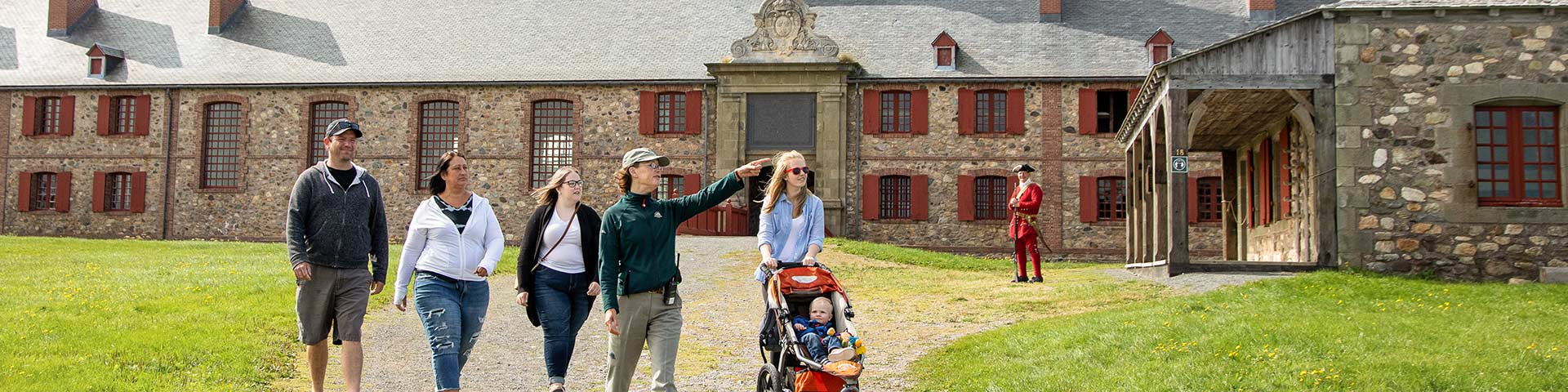 A group of visitors walk with a tour guide at the Fortress of Louisbourg