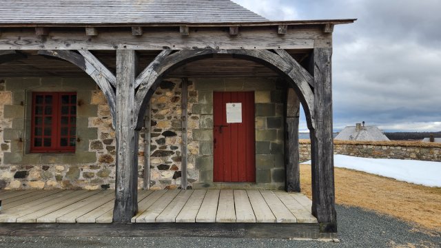 The front of the Guardhouse, showcasing the rounded wooden porch entryway and red door.