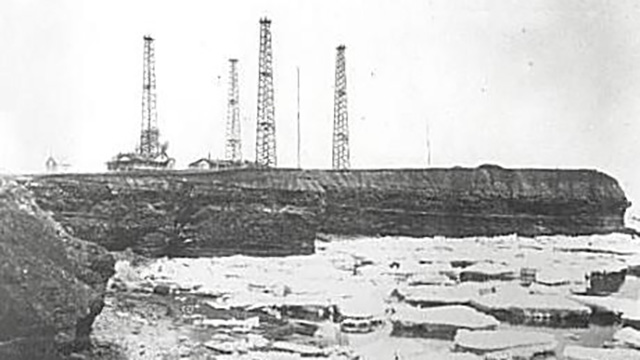 An historical photo of radio towers on an oceanside cliff