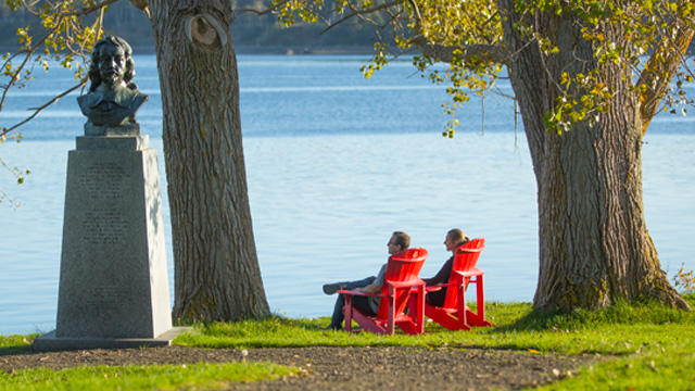 Des visiteurs admirent le panorama de la rivière depuis les chaises rouges.