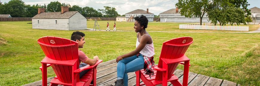 A young couple relaxing in the Red Chairs, Fort George National Historic Site.