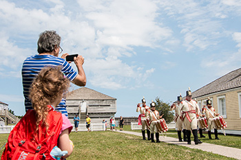 Les visiteurs regardent le corps de fifres et tambours défiler au Fort George.
