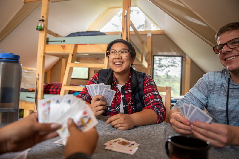 Campers play cards in a Parks Canada oTENTik