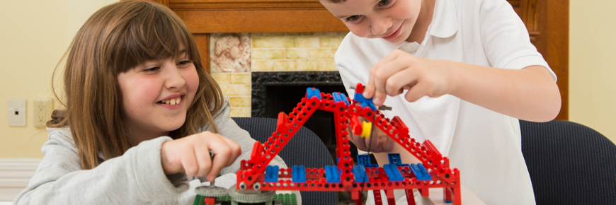 Deux enfants jouent avec un pont modèle.