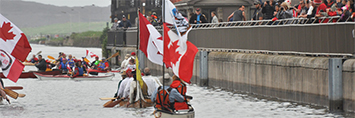 Canoes bearing Canadian flags are floating in the canal.