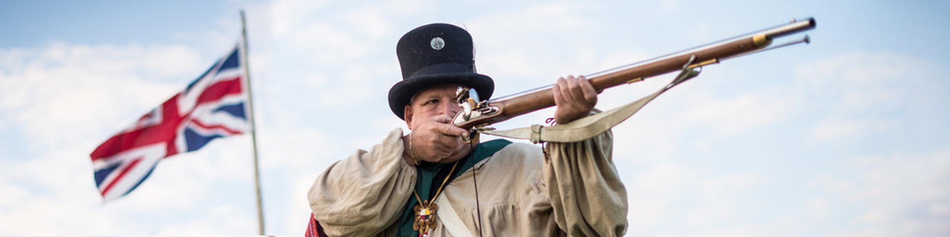 A staff member in costume aiming a musket.
