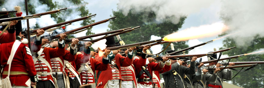 Soldiers in red coats, firing rifles.