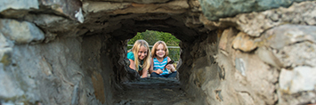Two children exploring a stone ruin.