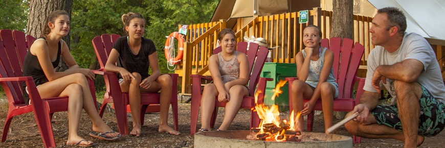  Une famille assise autour d'un feu de camp à l'extérieur d'otentik