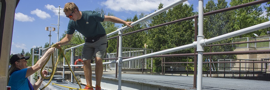 A Parks Canada student helping a boater at a lock station. 