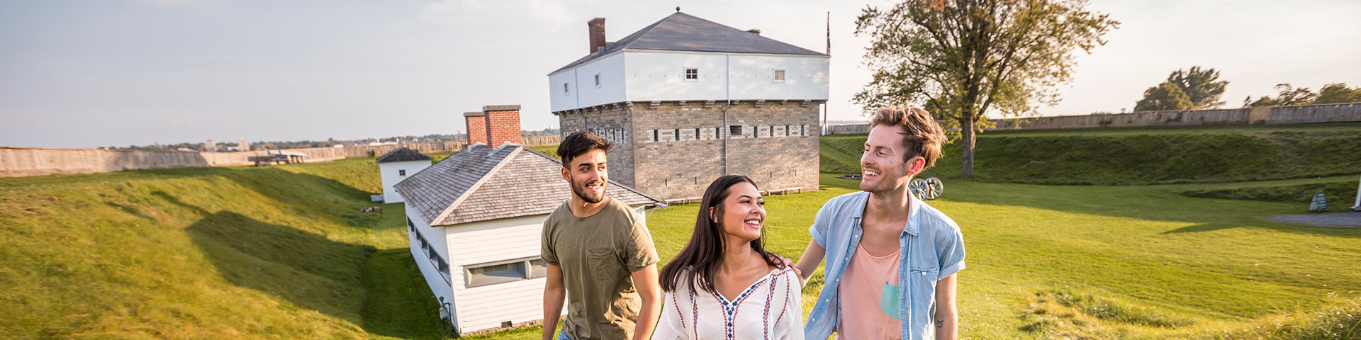 A group of teens walks up a hill in front of a historic fort. 
