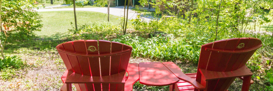 Deux chaise rouges de Parcs Canada, avec vue de la maison historique