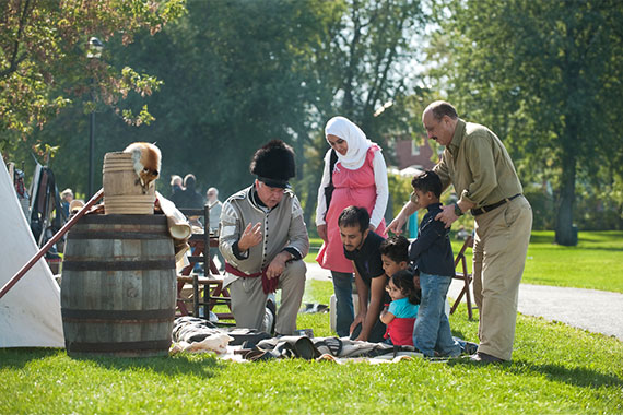 Costumed interpreter and visitors at re-enactment of an 1812-era encampment at Fort Chambly National Historic Site.