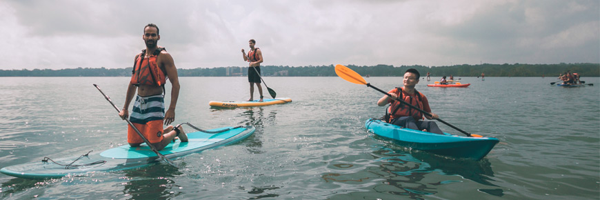 Hommes souriant qui naviguent sur une planche à pagaie et kayak