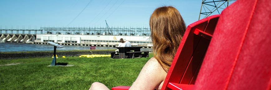 young woman sitting on a red chair near the canal.