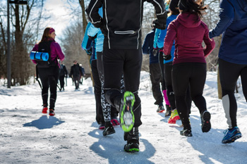 Group of runners running on winter trail road in snow