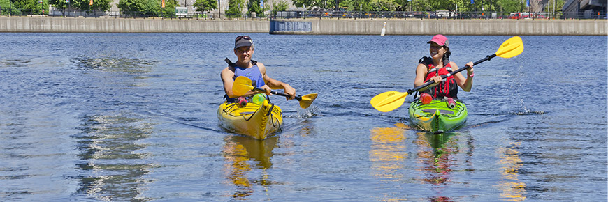 A man and a woman in a kayak on the waters of the Lachine Canal