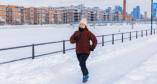 A woman running on a groomed snow path beside the frozen Lachine Canal.