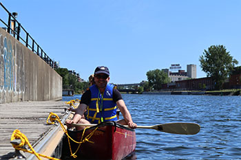 Homme souriant à bord d'un canot accosté à un quai