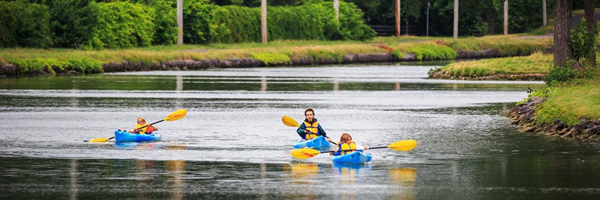 2 enfants et un employé de Parcs Canada en canot sur le canal.