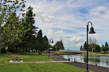 À gauche : espaces verts et tables à pic-nique. à droite, des lampadaires sur le bord du canal