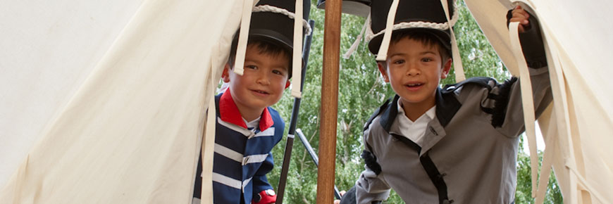 Two twin kids dressed in soldiers enter a tent