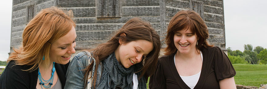 Trois jeunes femmes souriantes devant le blockhaus