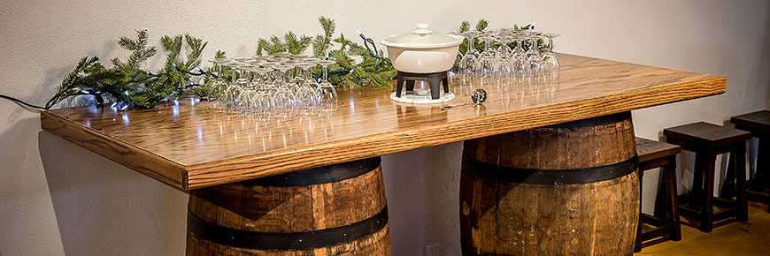 Table de chêne assise sur deux barils et remplie de coupes à vin