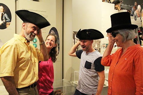 Visiteurs riant lors de l'essai de chapeaux de feutre