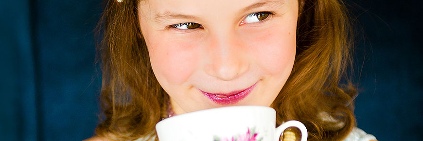 Young smiling girl about to taste a cup of tea