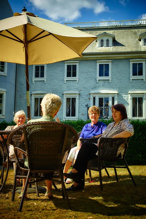 Ladies chat under an umbrella in the backyard of the Manoir Papineau