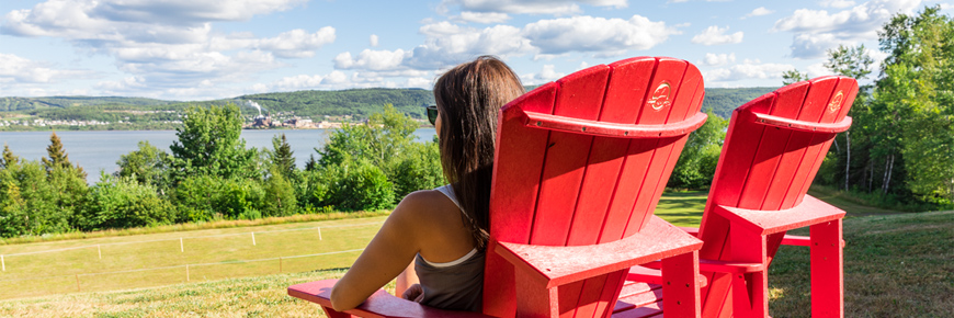 Woman sitting on a red chair looking at Restigouche river