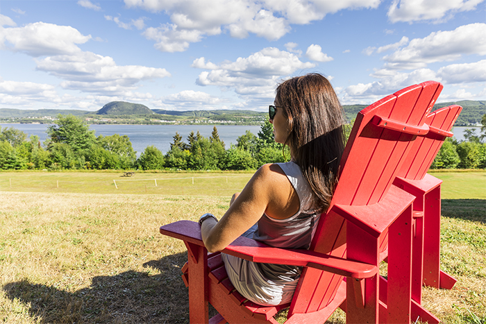 Woman sitting on a red chair looking at Restigouche river
