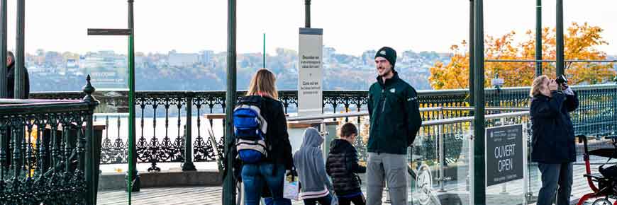 An adult and two children approaching stairs with a Parks Canada guide at the entrance of the historic site on Dufferin Terrace.