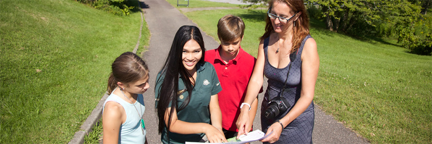 A Parks Canada guide giving indications on a map to a young family