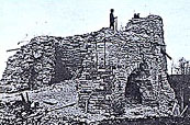 A photography showing the blast furnace of the ruined Forges circa 1900. We can see inside the furnace as the masonry of one of the four walls crushed down. There is on this vestige a man looking far away.