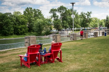 Two persons relaxing on red chairs with Parks Canada logo on it