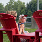 Family sitting on two red Saint-Ours Canal Adirondack chairs.